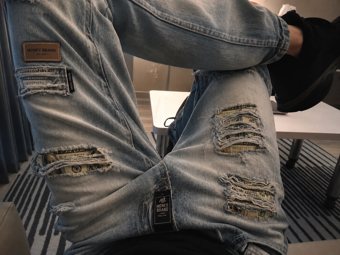 Money Brand historical denim concept with distressed currency-print panels, a leather brand patch and hangtag